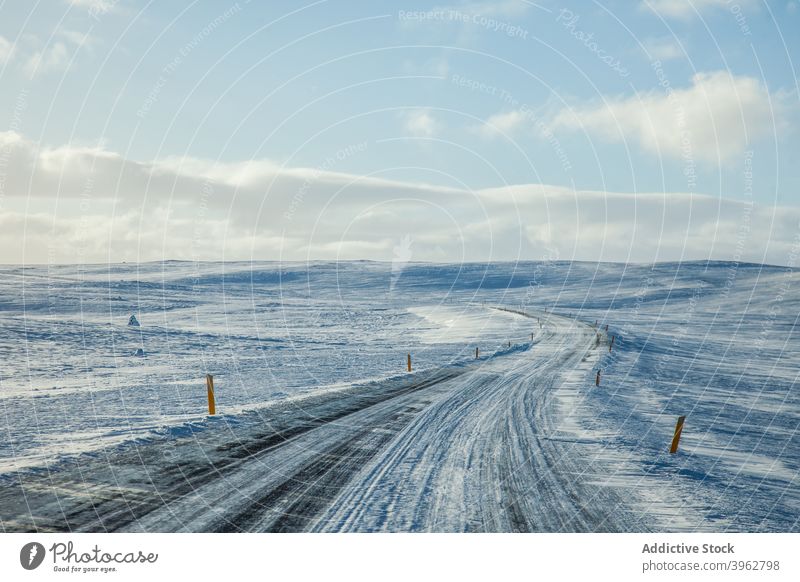 Verschneite Straße an einem sonnigen Tag im Winter Schnee leer Fahrbahn Landschaft Weg endlos Island Gelände blau Himmel wolkig kalt Natur Saison Wetter