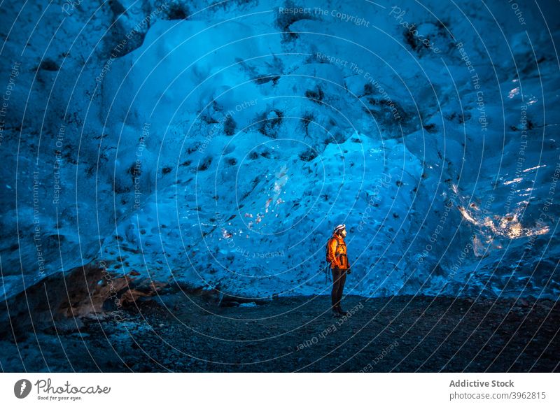 Reisender in Eishöhle im Winter stehend Höhle Abenteuer Entdecker Licht kalt gefroren Natur Island Tourismus blau Landschaft Felsen erkunden arktische malerisch