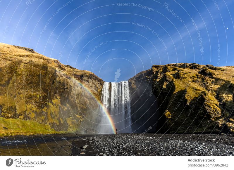 Explorer stehend in der Nähe Wasserfall am sonnigen Tag Regenbogen Reisender Berge u. Gebirge Urlaub Landschaft erstaunlich fließen strömen Tourismus Island