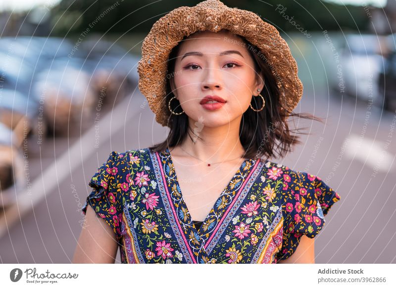 Stilvolle ethnische Frau auf Parkplatz trendy Kleid Outfit Strohhut Weide Handtasche parken Sommer asiatisch charmant Mode Hut stehen Inhalt Bekleidung Kleidung