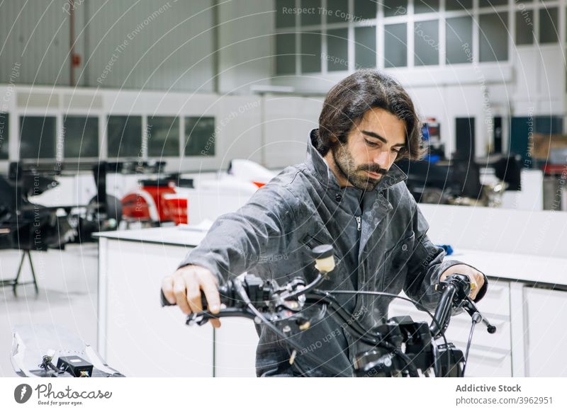 Fleißiger Techniker in der Motorradwerkstatt Mechaniker benutzerdefiniert Mann untersuchen Arbeitsbekleidung prüfen Lenker männlich Werkstatt Dienst modern hell