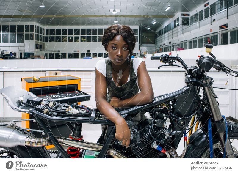 Schwarze Frau mit Motorrad bei der Arbeit in der Werkstatt Mechaniker benutzerdefiniert professionell Fahrzeug Reparatur versammeln Afroamerikaner schwarz