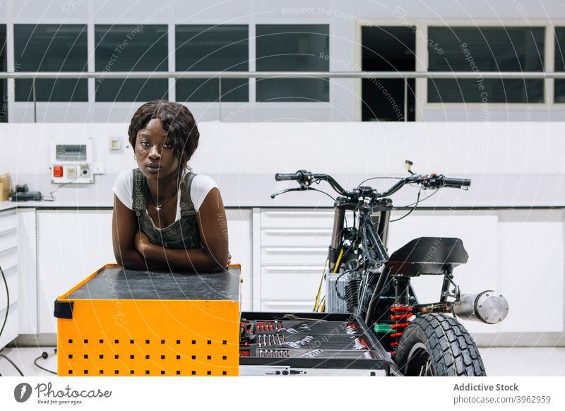 Schwarze Frau mit Motorrad bei der Arbeit in der Werkstatt Mechaniker benutzerdefiniert professionell Fahrzeug Reparatur versammeln Afroamerikaner schwarz
