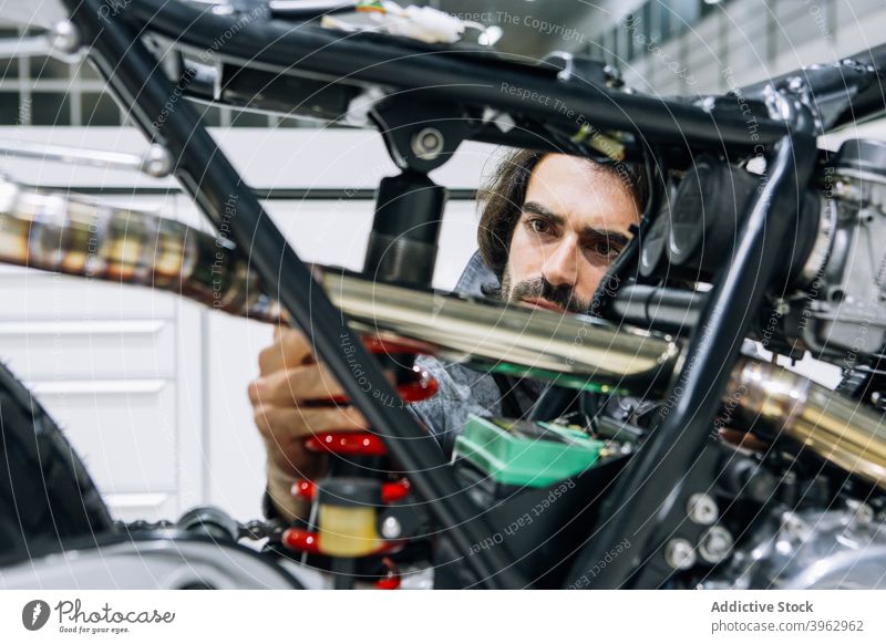 Mechaniker bei der Untersuchung des Stoßdämpfers eines Motorrads Werkstatt untersuchen Mann benutzerdefiniert Techniker prüfen männlich Arbeitsbekleidung Dienst