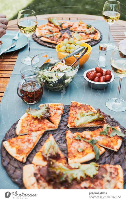 Abendessen in einem Hausgarten. Pizza, Salate, Früchte und Weißwein auf dem Tisch in einem Hinterhof Getränk Feier Speise trinken Essen Festessen Lebensmittel