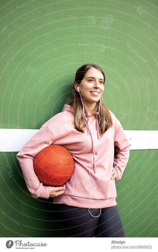 junge langhaarige Frau hält einen Basketball gegen grüne Wand Sport Person Fitness Training Athlet Ball Beteiligung Mädchen Spieler Übung Gesundheit Lifestyle