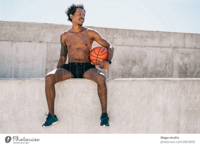 Afro-Athlet Mann hält einen Basketball-Ball im Freien. Sport urban sportlich Stehen genießen Ausdruck aktiv Hand Übung Erholung Fitness Training Blick Aktivität