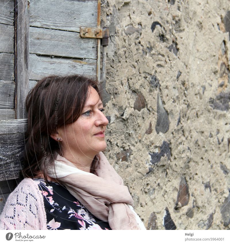 Porträt im Halbprofil einer brünetten langhaarigen Frau vor einer historischen Häuserfassade Mensch Dame Lächeln schauen Wand Mauer Fassade Holztür Schal Jacke