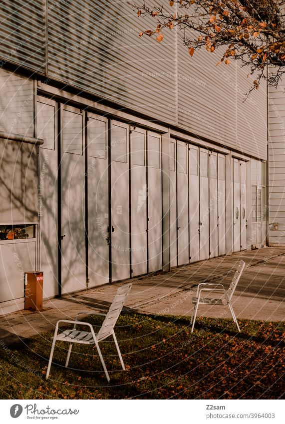 Stühle im Außenbereich einer Industriehalle industriehalle Einfahrt Tore Produktion warme farbe pausieren Erholung mittagspause Bäume Schatten licht herbst
