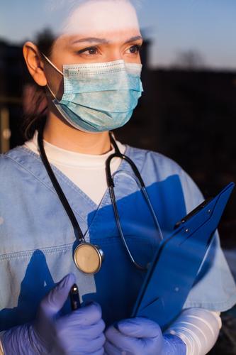 Arzt schaut durch das Fenster blau Pflege Klinik Korona Coronavirus COVID Krankheit Notfall Seuche erschöpft Gesicht Angst Frau Frontlinie Frustration Glas