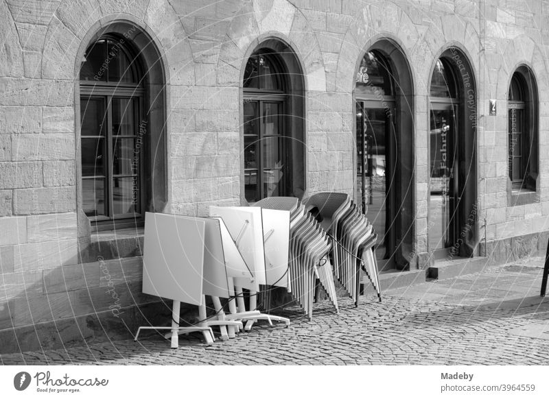 Zusammengeklappte Tische und gestapelte Stühle vor einem Bristro mit Rundbogenfenstern auf dem Römerberg in Frankfurt am Main in Hessen Restaurant Gastronomie