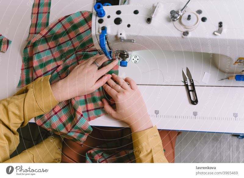 Draufsicht auf eine Frau bei der Arbeit mit der Nähmaschine in ihrer Werkstatt Maschine Nähen Gewebe Schneider Material Näherin Bekleidung Nadel Handwerk Faser