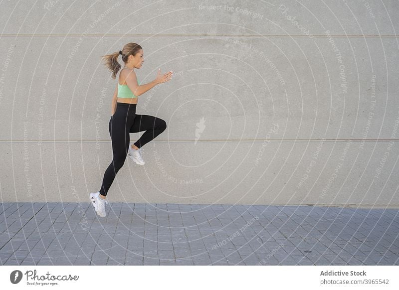 Sportlerin springt beim Training in der Stadt springen aktiv Sprung Energie Aufwärmen Großstadt Straße Frau Sportkleidung Fitness Sportbekleidung Gesundheit