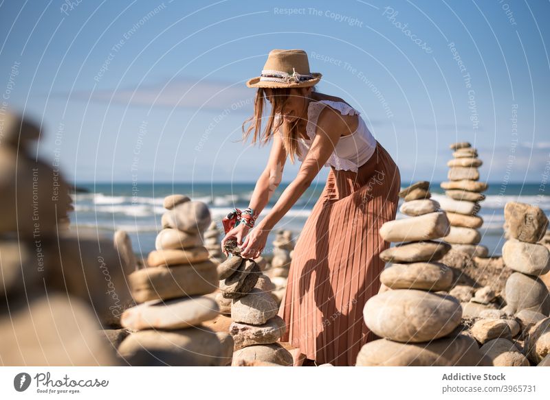 Glückliche junge weibliche Tourist erstellen zen Steine auf Sandstrand im Sonnenlicht Frau Pyramiden Lächeln heiter genießen Strand Meer Urlaub Reisender