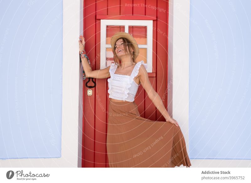 Fröhlich stilvolle junge Dame steht in der Nähe der Tür des typischen Haus am sonnigen Tag Frau Glück Lächeln Mode Stil Urlaub Architektur Fassade Tourist