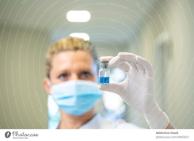Arzt in Maske mit Impfstoff in Ampulle Coronavirus Frau Chemikalie Abhilfe liquide Glas Mundschutz Sanitäter Klinik COVID19 Handschuh medizinisch Medizin