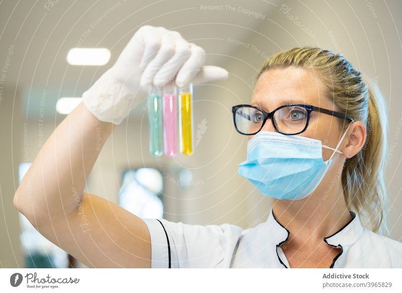 Wissenschaftler mit Reagenzgläsern im Labor Reagenzglas Frau Flasche Chemikalie liquide Glas Probe Mundschutz Latex ernst verschiedene Experiment farbenfroh