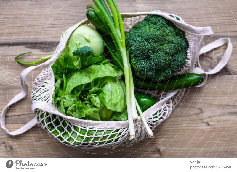 Rohes grünes Gemüse in einer wiederverwendbaren Netz Einkaufstasche auf einem Holztisch roh frisch Diät Vegetarische Ernährung Hintergrundbild Tisch organisch