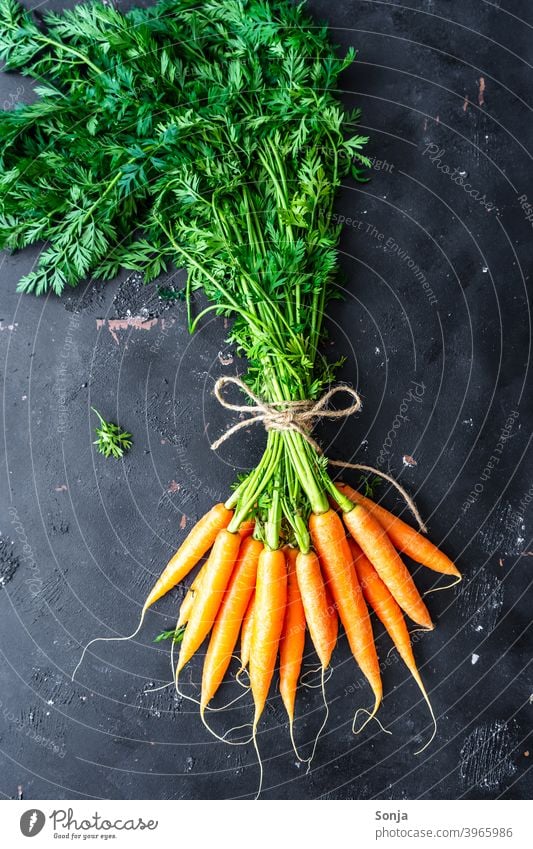 Ein Bund Karotten auf einem schwarzen Hintergrund grünzeug Bund 19 orange Gemüse Karotin Vegetarische Ernährung Bioprodukte Lebensmittel Farbfoto Gesundheit
