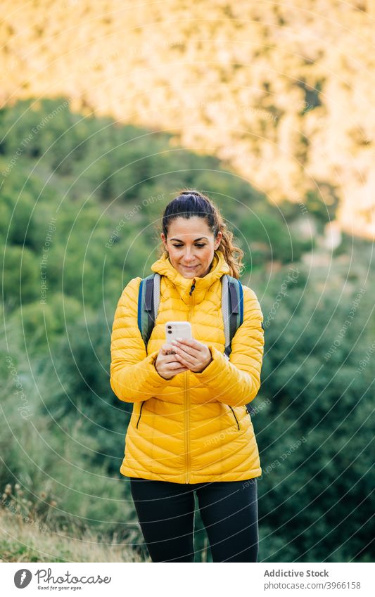 Reisende Frau in Oberbekleidung mit Smartphone in der Natur Wanderer Browsen Trekking Saison Hügel Surfen Mobile Telefon Lächeln reisen Abenteuer benutzend warm