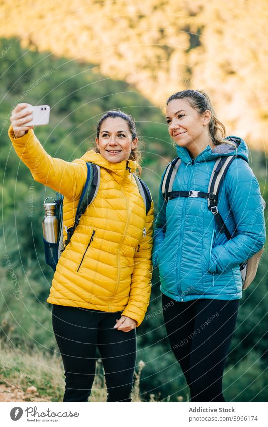 Lächelnde reisende Frauen nehmen Selfie in der Natur Trekking Wanderer Zusammensein Smartphone jung Apparatur Mobile Freude heiter Gerät Optimist Telefon