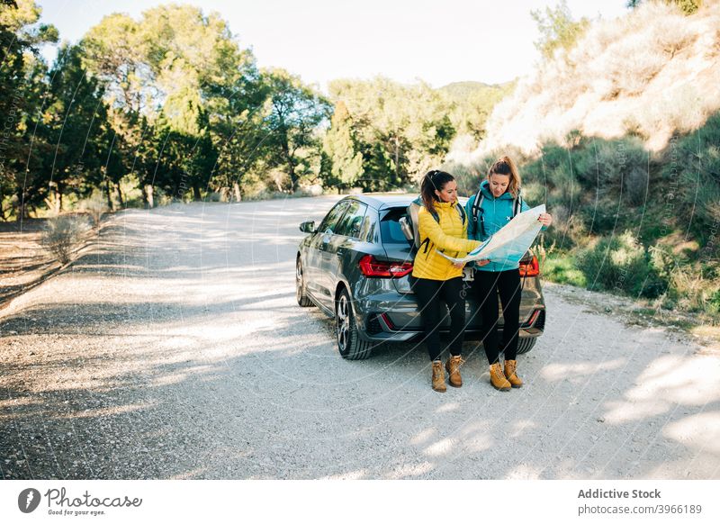 Weibliche Reisende navigieren mit Karte auf der Straße Frauen Landkarte lesen PKW Suche sich orientieren Reisender Route Regie Zusammensein Papier reisen