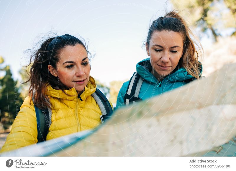 Weibliche Reisende navigieren mit Karte auf der Straße Frauen Landkarte lesen PKW Suche sich orientieren Reisender Route Regie Zusammensein Papier reisen