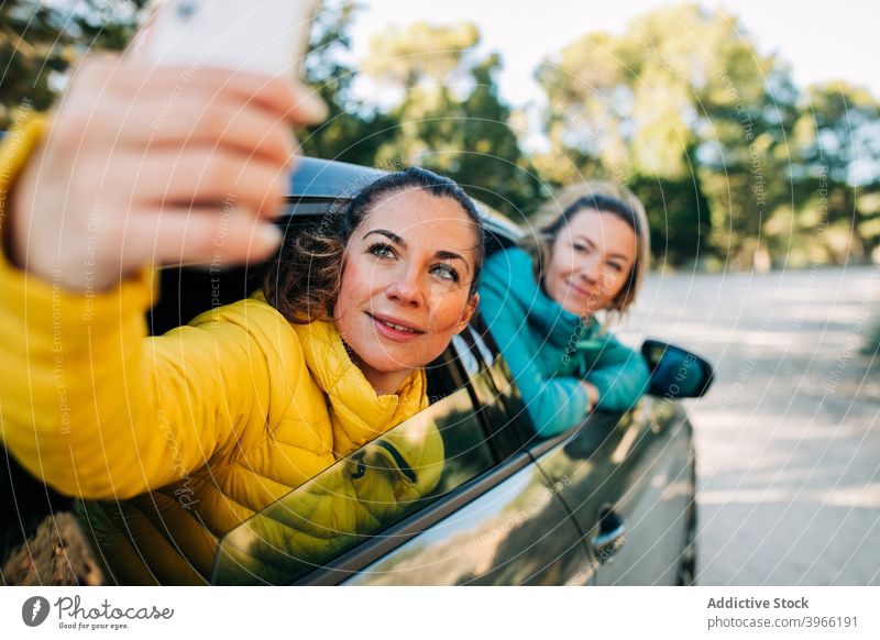 Frauen nehmen Selfie im Auto PKW Zusammensein Freund Selbstportrait Automobil Smartphone gucken Straße Lächeln Freundschaft Fenster Glück Apparatur Gerät