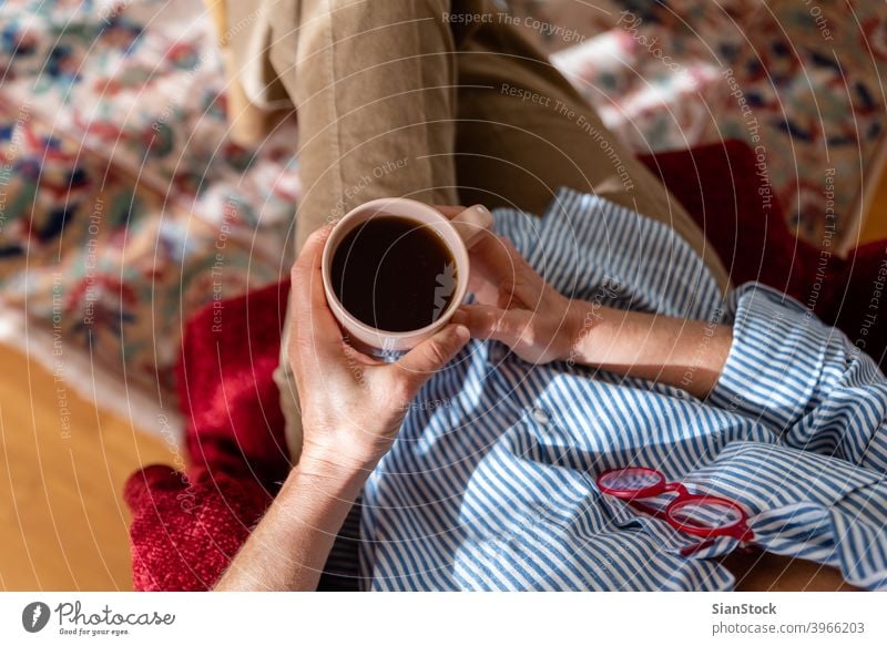 Hände einer reifen Frau halten eine Tasse Kaffee, Ansicht von oben Raum zuschauend Mitteilung Freizeit älter Top rot Brille Armsessel Teppich elegant Halt