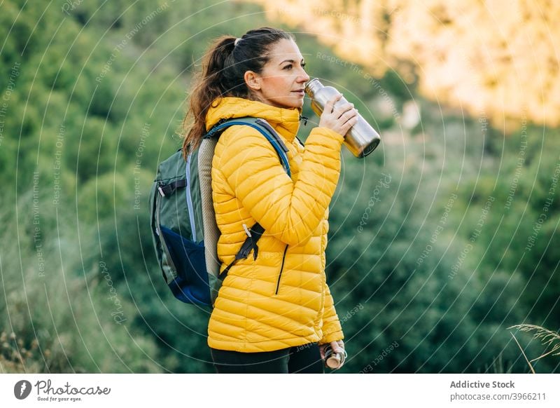 Reisende Frau trinkt Wasser in der Natur Wanderer trinken Trekking Flasche Saison Durst Hydrat warm Jacke reisen jung Metall Abenteuer Aktivität Tourist Dame