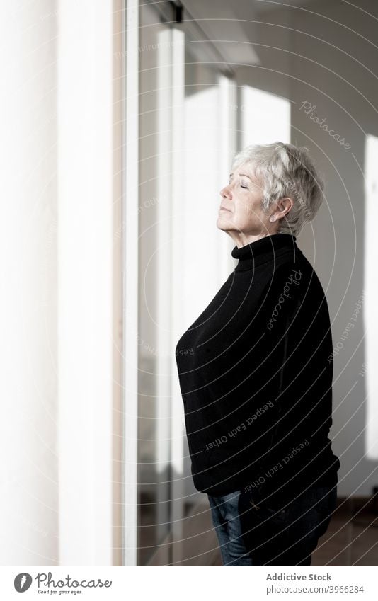 Entspannte Seniorin zu Hause am Fenster Frau Kaukasier älter heimwärts Europäer Lifestyle Porträt Menschen entspannend in den Ruhestand getreten Gelassenheit