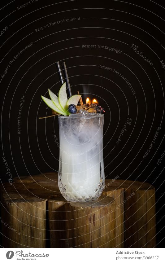 Glas Alkohol-Cocktail mit Apfelscheiben und brennenden Gewürzen trinken farbenfroh alkoholisch Bar frisch Sommer Likör kalt Pub Tisch cool Lifestyle Zimt Holz