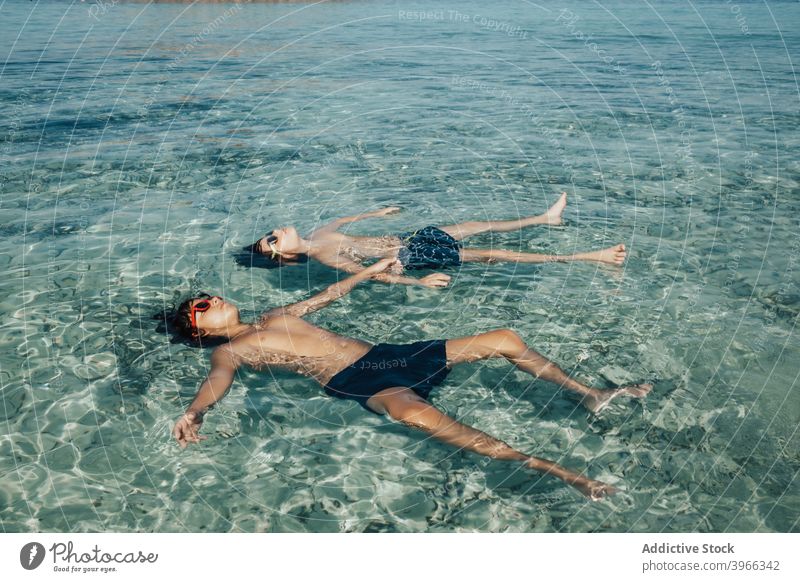 Zwei Jungen entspannt am Strand im Sommer Kind aussruhen MEER Wasser aqua Strandkinder blau Kaukasier Kindheit genießen Europäer Schutzbrille Fröhlichkeit Glück