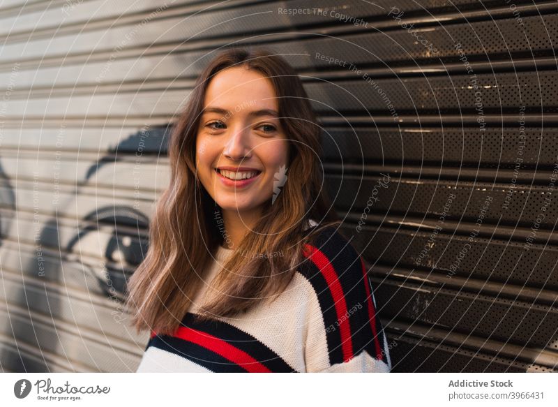 Fröhliche junge Frau steht in der Nähe der Wand Glück heiter Teenager Lächeln Optimist froh positiv Jugendlicher tausendjährig brünett Freude Lifestyle Glee