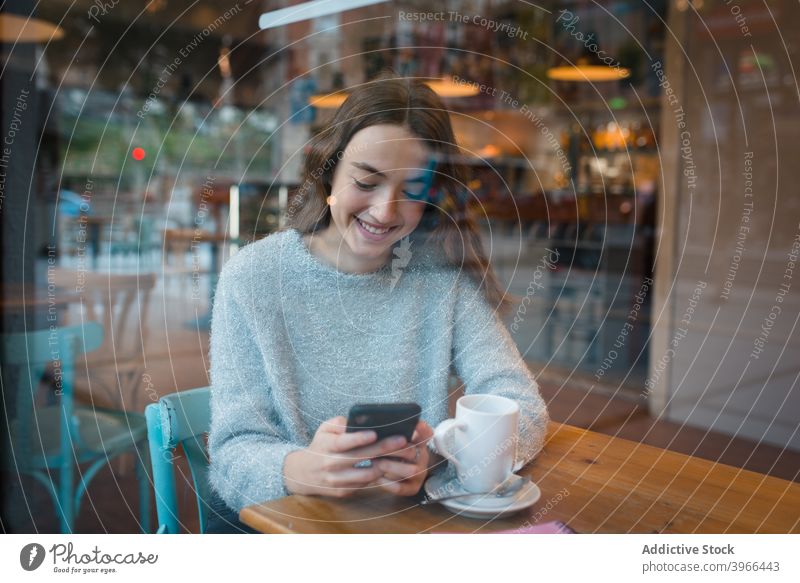 Frau beim Surfen auf dem Smartphone im Café Browsen zuschauend Texten Lächeln diskutieren sprechen reden Kantine sich[Akk] entspannen Kälte Gerät Tisch charmant