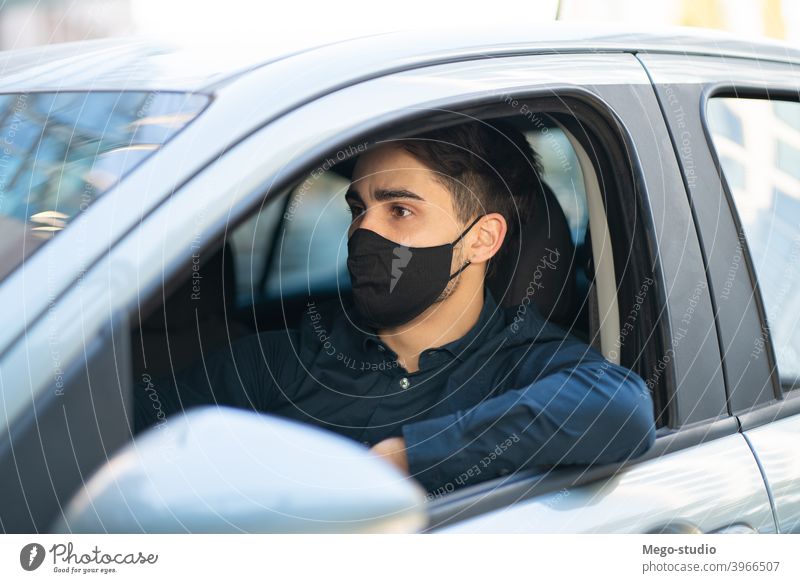 Junger Mann am Steuer seines Autos. Gesicht Mundschutz Laufwerk PKW Sitzen Freizeit Straße reisen Schutzmaske Gesichtsmaske fahren Großstadt Verkehr