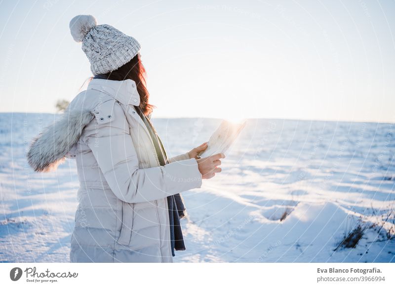schöne junge Frau bei Sonnenuntergang in verschneiten Berg Lesen einer Karte. Reisen, Natur und Technologie-Konzept. Wintersaison Landkarte Berge u. Gebirge