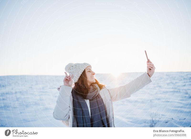 schöne junge Frau bei Sonnenuntergang in verschneiten Berg mit Handy. Natur und Technik Konzept. Wintersaison Technik & Technologie Berge u. Gebirge Schnee