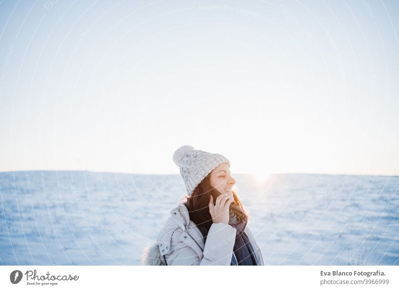 schöne junge Frau bei Sonnenuntergang in verschneiten Berg sprechen auf Handy. Natur und Technik Konzept. Wintersaison Technik & Technologie Berge u. Gebirge
