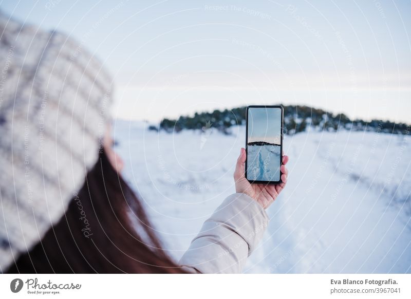 Rückenansicht von Backpacker Frau Wandern in verschneiten Berg ein Bild der Landschaft mit mobile phone.winter season. Natur und Technik Handy