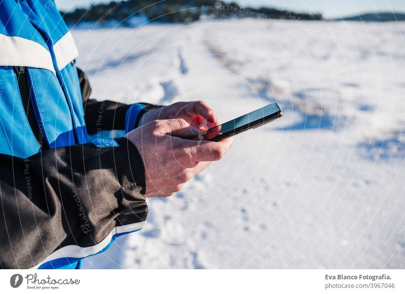 Nahaufnahme von Mann Wandern in verschneiten Berg in einem sonnigen Tag mit Handy. Technik und Natur. Wintersaison Technik & Technologie abschließen Schnee
