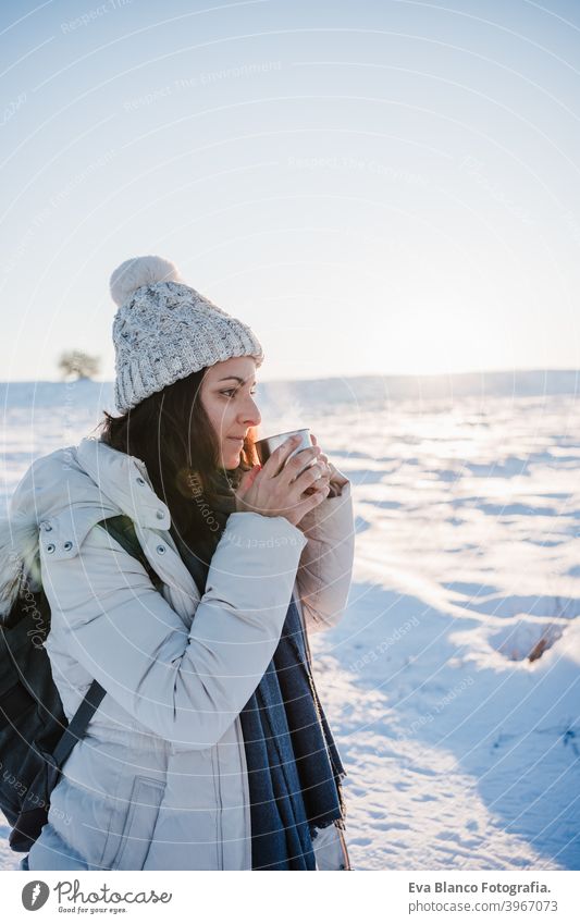 schöne junge Frau bei Sonnenuntergang in verschneiten Berg hält eine Tasse heißen Tee. Reisen und Natur Konzept. Wintersaison heißer Tee Thermoskanne