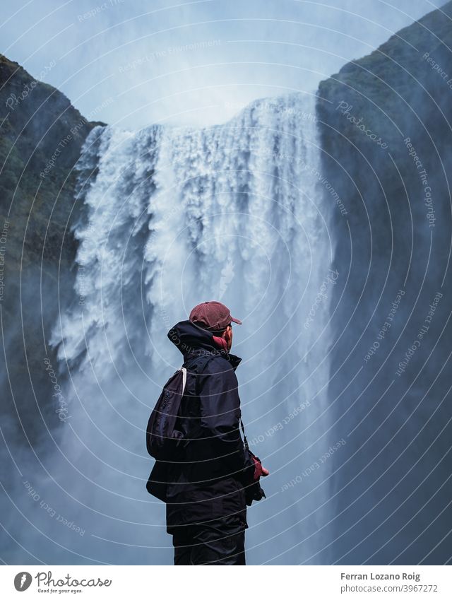 Porträt eines Mannes mit Blick auf einen Wasserfall Island Junger Mann kalt blau Natur Berge u. Gebirge Paradies