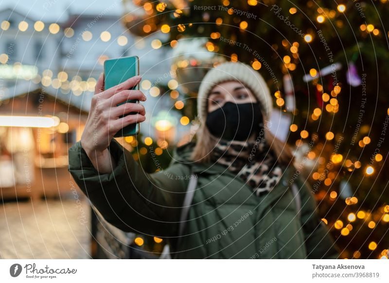 Frau in Gesichtsmaske nimmt Selfie Weihnachten Markt Mundschutz Schutz Lifestyle Fotografieren Feiertag Coronavirus Winter Tallinn Estland Großstadt Saison