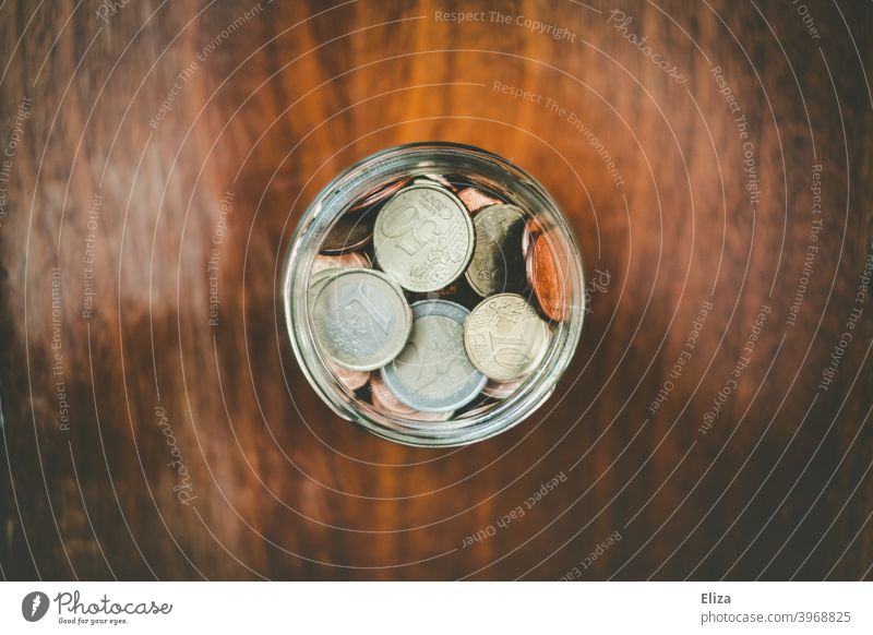 Ein Glas voll mit gesparten Münzen. Geldmünzen sparen Hand Vogelperspektive Spardose Euro Bargeld stoppen Kleinvieh kleine Änderung Holz gespeichert Verwahrung