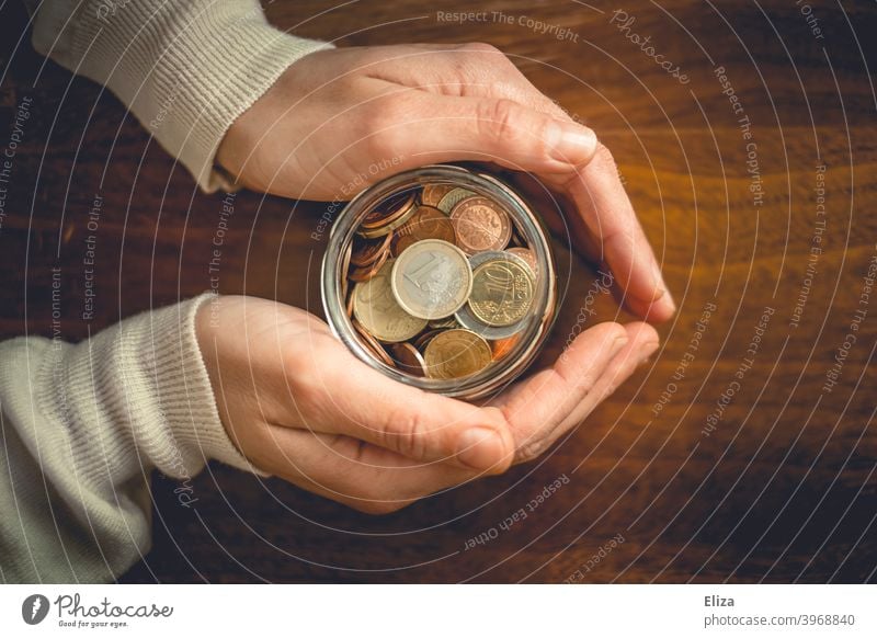 Hände halten ein Glas voller Geldmünzen. Sparen. Hand Vogelperspektive Spardose Euro Bargeld Münzen Kleinvieh sparen Kleingeld Holz Vermögen Finanzen angespart