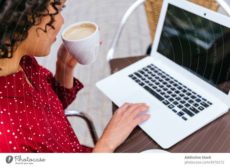 Anonyme Frau mit Laptop und Kaffee trinken sitzen auf Café Terrasse besinnlich Arbeit abgelegen freiberuflich jung ethnisch hispanisch Geschäftsfrau Gerät