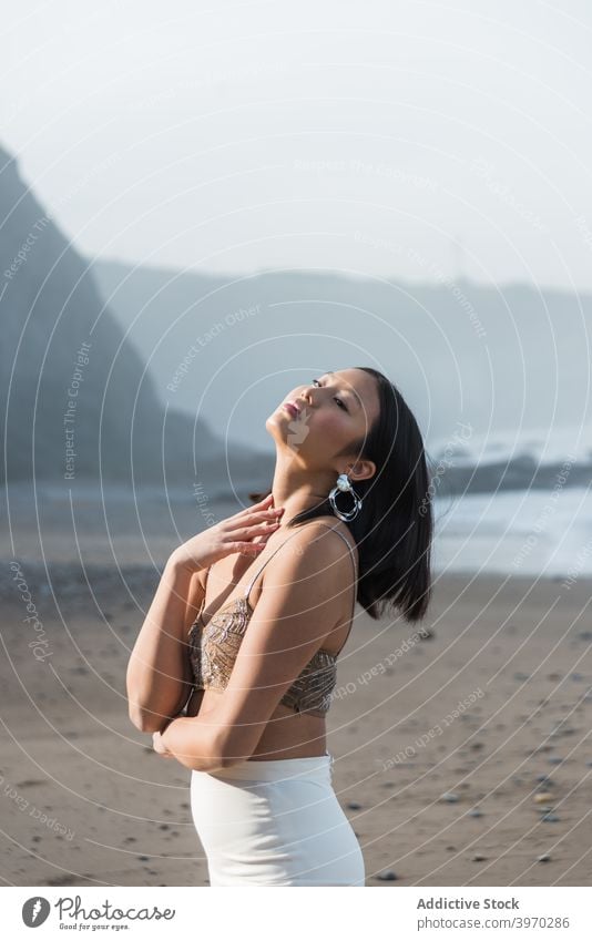 Sinnliche ethnische Frau steht auf Sandstrand sinnlich Strand genießen Stil Mode schlank jung elegant Sommer asiatisch Verlockung Sonnenlicht trendy