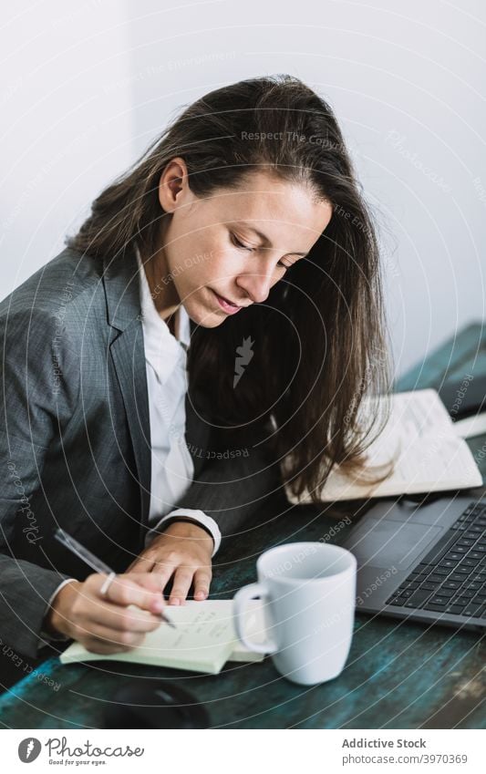 Geschäftsfrau macht Notizen während des Arbeitstages zu Hause zur Kenntnis nehmen schreiben abgelegen freiberuflich beschäftigt Plan formal Arbeitsplatz Frau