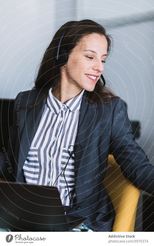 Lächelnde Frau mit Headset und Laptop am Arbeitsplatz Telearbeit abgelegen heiter formal Kommunizieren positiv jung Büro Gerät Apparatur Lifestyle online